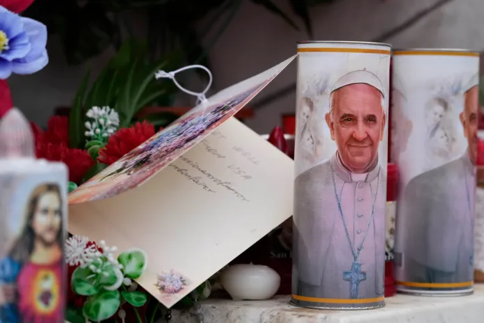 Velas con la imagen del papa Francisco se ven a los pies de la estatua al fallecido papa Juan Pablo II ante la Policlínica Agostino Gemelli en Roma,. Foto La Hora: AP