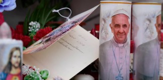 Velas con la imagen del papa Francisco se ven a los pies de la estatua al fallecido papa Juan Pablo II ante la Policlínica Agostino Gemelli en Roma,. Foto La Hora: AP