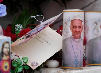 Velas con la imagen del papa Francisco se ven a los pies de la estatua al fallecido papa Juan Pablo II ante la Policlínica Agostino Gemelli en Roma,. Foto La Hora: AP