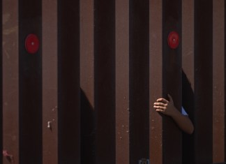 Foto de archivo que muestra a un niño se ha aferrado a la valla fronteriza de EE.UU. mientras espera a la Patrulla Fronteriza. Foto La Hora: EFE