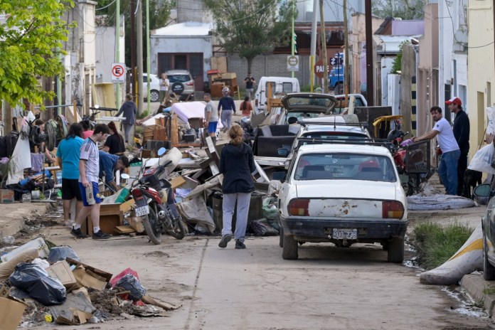 Fotografía que muestra personas caminando entre escombros ocasionados por una inundación en Bahía Blanca (Argentina). Foto La Hora: EFE