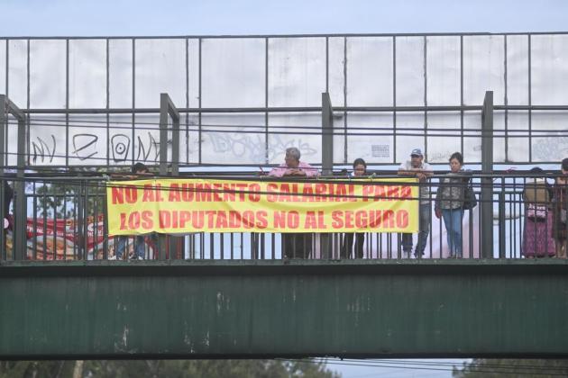 Manifestantes en el bloqueo frente a la colonia La Bethania, zona 7 colocan mantas rechazando el seguro contra terceros obligatorio presentado por la cartera del Interior.  Fotos La Hora: Fabricio Alonzo.