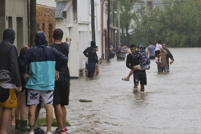 Varias personas caminan en medio de una inundación debido a fuertes lluvias este viernes, en Bahía Blanca (Argentina). Foto La Hora: EFE