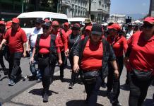 Juzgado de Trabajo de Izabal ordena al STEG de Joviel Acevedo cesar medidas de hecho Sandra Carolina Méndez Duarte, dirigente de la filial del STEG en Zacapa, frente a Joviel Acevedo con una botella en la mano y chaleco negro abierto. Foto La Hora: Daniel Ramírez