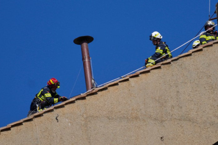 Bomberos instalan la chimenea del cónclave en el tejado sobre la Capilla Sixtina, donde los cardenales se reunirán para elegir al nuevo papa, en el Vaticano, el 2 de mayo de 2025. Foto La Hora: AP