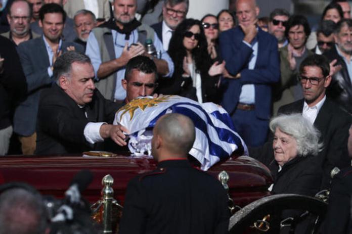 El presidente de Uruguay, Yamandú Orsi (i), extiende una bandera sobre el ataúd del exmandatario uruguayo José "Pepe" Mujica, junto a Lucía Topolansky (d) este miércoles, en Montevideo. Foto La Hora: EFE.