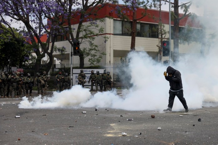 Un manifestante camina a través del humo de granadas de humo aturdidoras disparadas por agentes federales cerca de un Home Depot después de que el Servicio de Inmigración y Control de Aduanas (ICE) realizara una redada en Paramount, California, EE.UU. EFE/ALLISON DINNER