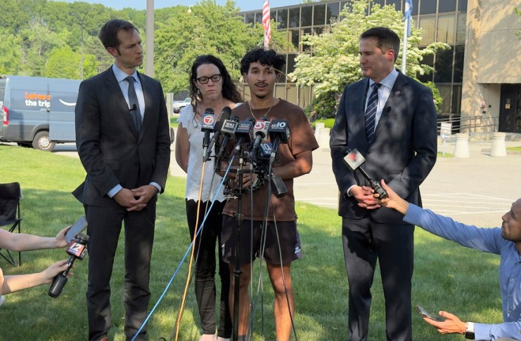 Marcelo Gomes da Silva, de 18 años, al centro, un estudiante de secundaria de Massachusetts que llegó a Estados Unidos cuando tenía 7 años de edad y fue detenido por agentes del Servicio de Inmigración y Control de Aduanas el sábado 31 de mayo de 2025, habla con la prensa después de ser liberado bajo fianza, acompañado de los representantes Seth Moulton, un demócrata por Massachusetts, a la derecha, y Jake Auchincloss, también demócrata del estado, el jueves 5 de junio de 2025, en Burlington, Massachusetts. (AP Foto/Rodrique Ngowi)