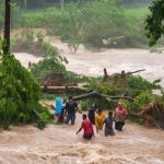 Grupo de personas intentando cruzar un río durante una crecida por la lluvia. Foto La Hora: Conred