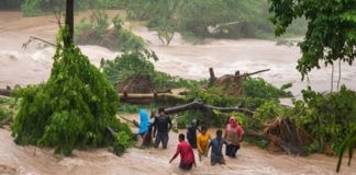 Grupo de personas intentando cruzar un río durante una crecida por la lluvia. Foto La Hora: Conred