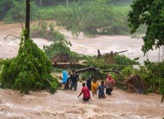 Grupo de personas intentando cruzar un río durante una crecida por la lluvia. Foto La Hora: Conred