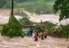 Grupo de personas intentando cruzar un río durante una crecida por la lluvia. Foto La Hora: Conred