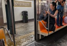 Usuario del metro de Nueva York se refugian sobre sus asientos ante inundaciones reportadas el 14 de julio por la noche.
