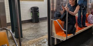 Usuario del metro de Nueva York se refugian sobre sus asientos ante inundaciones reportadas el 14 de julio por la noche.