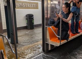 Usuario del metro de Nueva York se refugian sobre sus asientos ante inundaciones reportadas el 14 de julio por la noche.