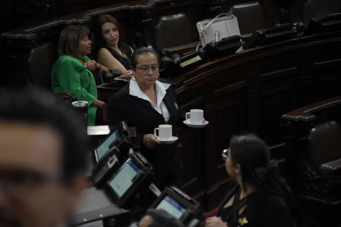 Una empleada 011 del Congreso sirve café a diputados en sus curules. Foto: La Hora / José Orozco.
