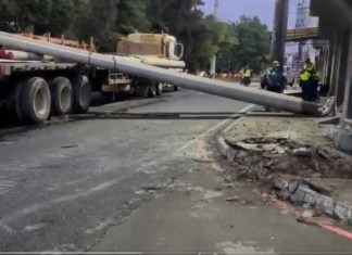 Un tráiler provocó serias complicaciones viales la mañana de este jueves 21 de agosto al derribar la carga de postes que transportaba sobre la ruta principal que conecta Prados de Villa Hermosa. Foto La Hora: Captura de Pantalla.