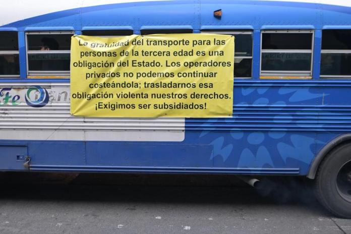 Manta vinílica con exigencias por pago de servicio gratuito de transporte al adulto mayor.