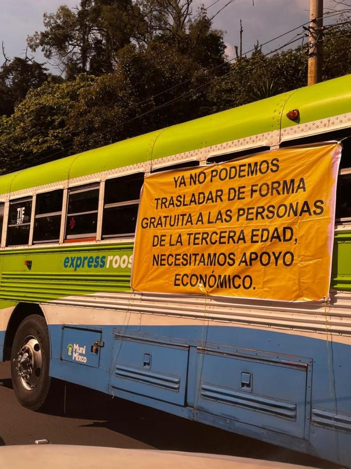 Manta vinílica con exigencias por pago de servicio gratuito de transporte al adulto mayor.