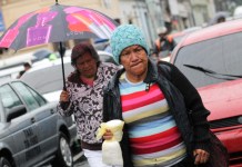 Dos señoras caminando, utilizando un paraguas y se encuentran bien abrigadas