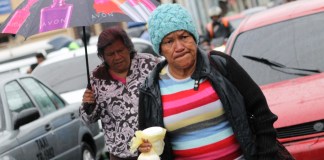 Dos señoras caminando, utilizando un paraguas y se encuentran bien abrigadas