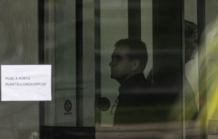 Fotografía que muestra al expresidente de Brasil Jair Bolsonaro (d) detrás de una puerta de vidrio este domingo, en la Superintendencia de la Policía Federal en Brasilia. Foto La Hora: EFE