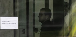 Fotografía que muestra al expresidente de Brasil Jair Bolsonaro (d) detrás de una puerta de vidrio este domingo, en la Superintendencia de la Policía Federal en Brasilia. Foto La Hora: EFE