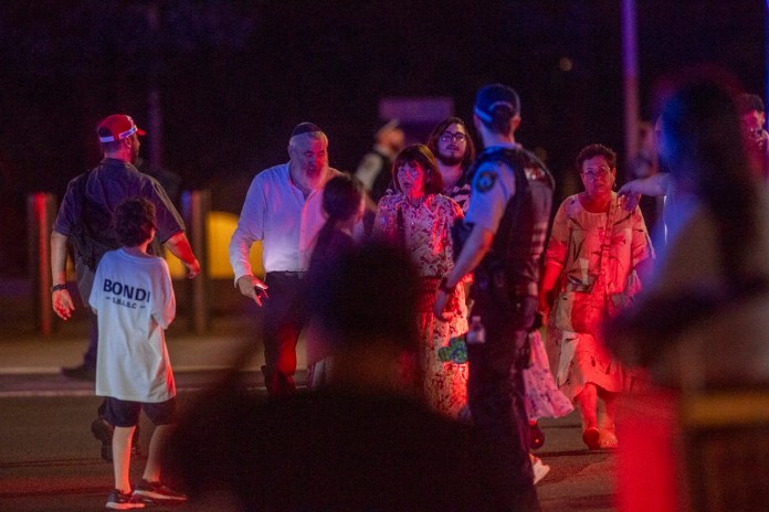 Un oficial de policía observa a la gente que desaloja la playa de Bondi en Sídney, Australia, donde este domingo al menos 10 personas han muerto, incluido uno los presuntos agresores, por un tiroteo que obligó a acordonar la zona y que ha causado también al menos 12 heridos. Foto La Hora: EFE/ Jeremy Piper