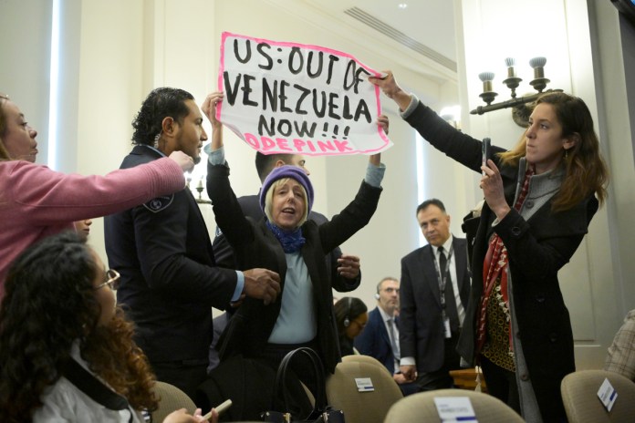 La integrante de la organización feminista CodePink, Medea Benjamin, sostiene un cartel durante una sesión extraordinaria del Consejo Permanente de la OEA en Washington. Foto La Hora: EFE