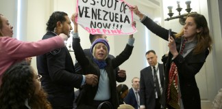 La integrante de la organización feminista CodePink, Medea Benjamin, sostiene un cartel durante una sesión extraordinaria del Consejo Permanente de la OEA en Washington. Foto La Hora: EFE