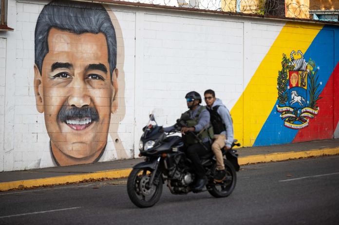 Personas transitan frente a un mural del presidente de Venezuela, Nicolás Maduro, este domingo en Caracas (Venezuela). EFE/ Ronald Peña R