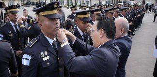 El ministro de Gobernación, Marco Antonio Villeda, coloca insignias en la graduación de los nuevos oficiales terceros de la Policía Nacional Civil. Foto: Ministerio de Gobernación
