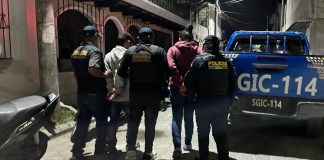 PNC conduce a dos hombres esposados a una patrulla.