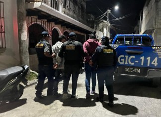 PNC conduce a dos hombres esposados a una patrulla.