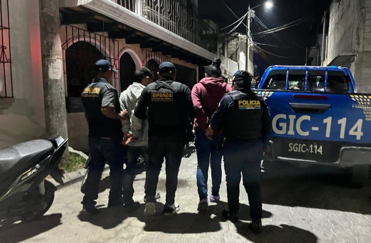 PNC conduce a dos hombres esposados a una patrulla.