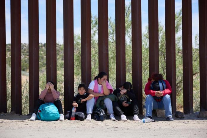 Una familia migrante espera en la frontera de Estados Unidos. Foto: EFE/EPA/Allison Dinner