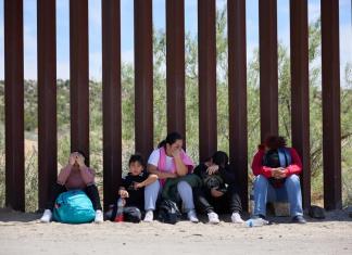 Una familia migrante espera en la frontera de Estados Unidos. Foto: EFE/EPA/Allison Dinner