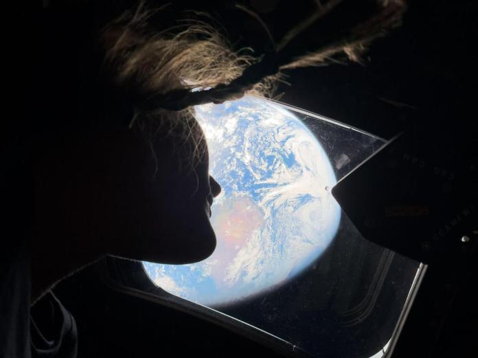 La astronauta de la NASA y especialista en la misión Artemis II, Christina Koch, mira desde una de las ventanas de la cabina principal de la nave espacial Orión, mirando hacia la Tierra, mientras la tripulación viaja hacia la Luna. Foto La Hora: NASA