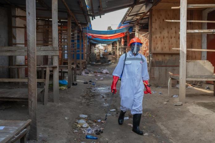 Un trabajador sanitario con equipo de protección desinfecta los puestos de un mercado de productos frescos en Bunia, provincia de Ituri, República Democrática del Congo, el pasado sábado. EFE/STRINGER