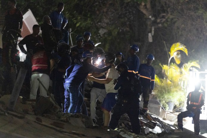 Integrantes de cuerpos de emergencia hablan con una persona este miércoles, luego de dos fuertes terremotos que sacudieron el Caribe venezolano en Caracas. Foto La Hora: EFE 