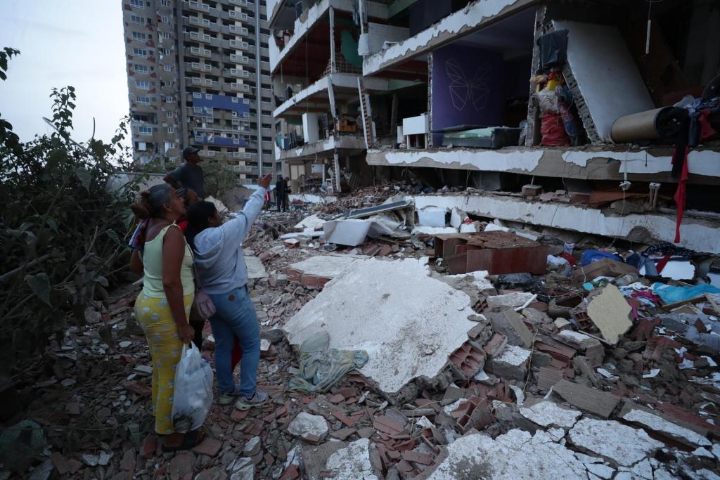 Residentes entre los escombros de uno de los bloques de viviendas dañados por los terremotos. Foto La Hora: EFE