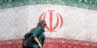 El mundo reacciona con optimismo cauteloso ante el anuncio de un acuerdo entre Irán y EE. UU. Mujer frente a bandera de Irán