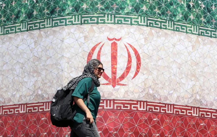 Asia urge a una navegación segura en Ormuz tras el anuncio de acuerdo entre EE.UU. e Irán Mujer frente a bandera de Irán