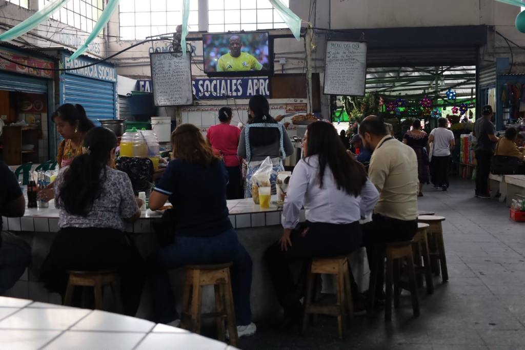 Un grupo de personas almuerzan y ven el partido de México 