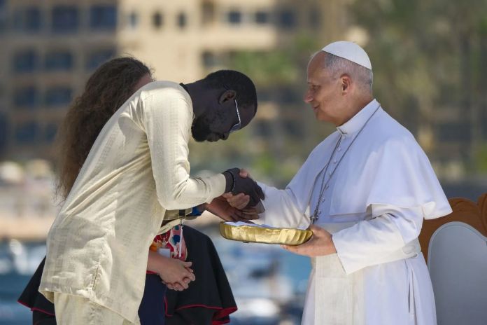 El papa León XIV recibe flores de dos voluntarios para protagonizar una ofrenda floral en el mar en recuerdo de los migrantes muertos. Foto La Hora: EFE