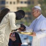 El papa León XIV recibe flores de dos voluntarios para protagonizar una ofrenda floral en el mar en recuerdo de los migrantes muertos. Foto La Hora: EFE