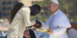 El papa León XIV recibe flores de dos voluntarios para protagonizar una ofrenda floral en el mar en recuerdo de los migrantes muertos. Foto La Hora: EFE