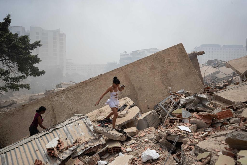 Personas caminan este jueves, entre los escombros de edificios afectados por los terremotos en La Guaira, Venezuela. Foto La Hora: EFE