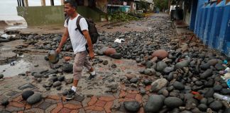 Una persona camina entre piedras desbordadas por el oleaje en el Puerto de La Libertad, El Salvador, tras la tormenta tropical Cristina. Foto La Hora: EFE