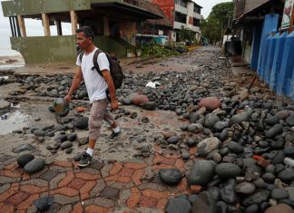 Una persona camina entre piedras desbordadas por el oleaje en el Puerto de La Libertad, El Salvador, tras la tormenta tropical Cristina. Foto La Hora: EFE